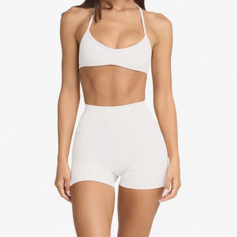 woman wearing a halter neck bra top and shorts gym set in white