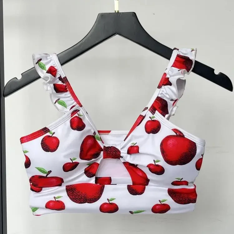 Bikini set with red apple pattern on a hanger against a neutral background