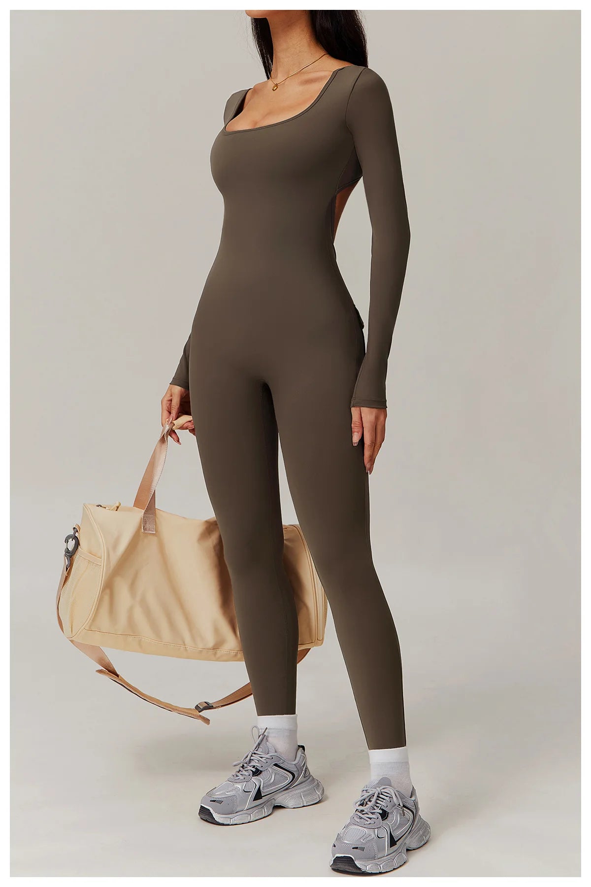 Person wearing a brown bodysuit with a beige bag on a light grey background